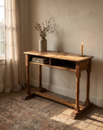 Antique wooden school desk as an entry console with stoneware vessel and candle