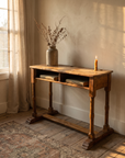 Antique wooden school desk styled in a warm room, two inkwell holes and books in the cubby