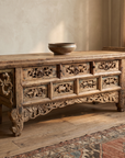 Long three-quarter view showing the full carved front and everted flanged ends of the altar table