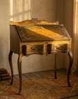 Gold Florentine desk beside linen curtains and an antique kilim rug