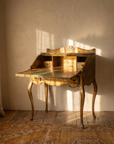 Italian Florentine gold secretary desk with the fall-front open, afternoon light across the writing surface