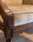 Macro of camel velvet, piped welting, and carved wood joinery