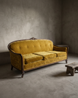 45 degree three-quarter view of the vintage gold velvet sofa showing the full camelback silhouette and carved crest