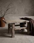 Wormwood Coffee Table lifestyle hero, styled in a greige plaster room with stoneware vessels and draped linen
