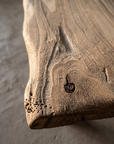Macro detail of the live edge, grain, and natural wormhole cluster on the tabletop