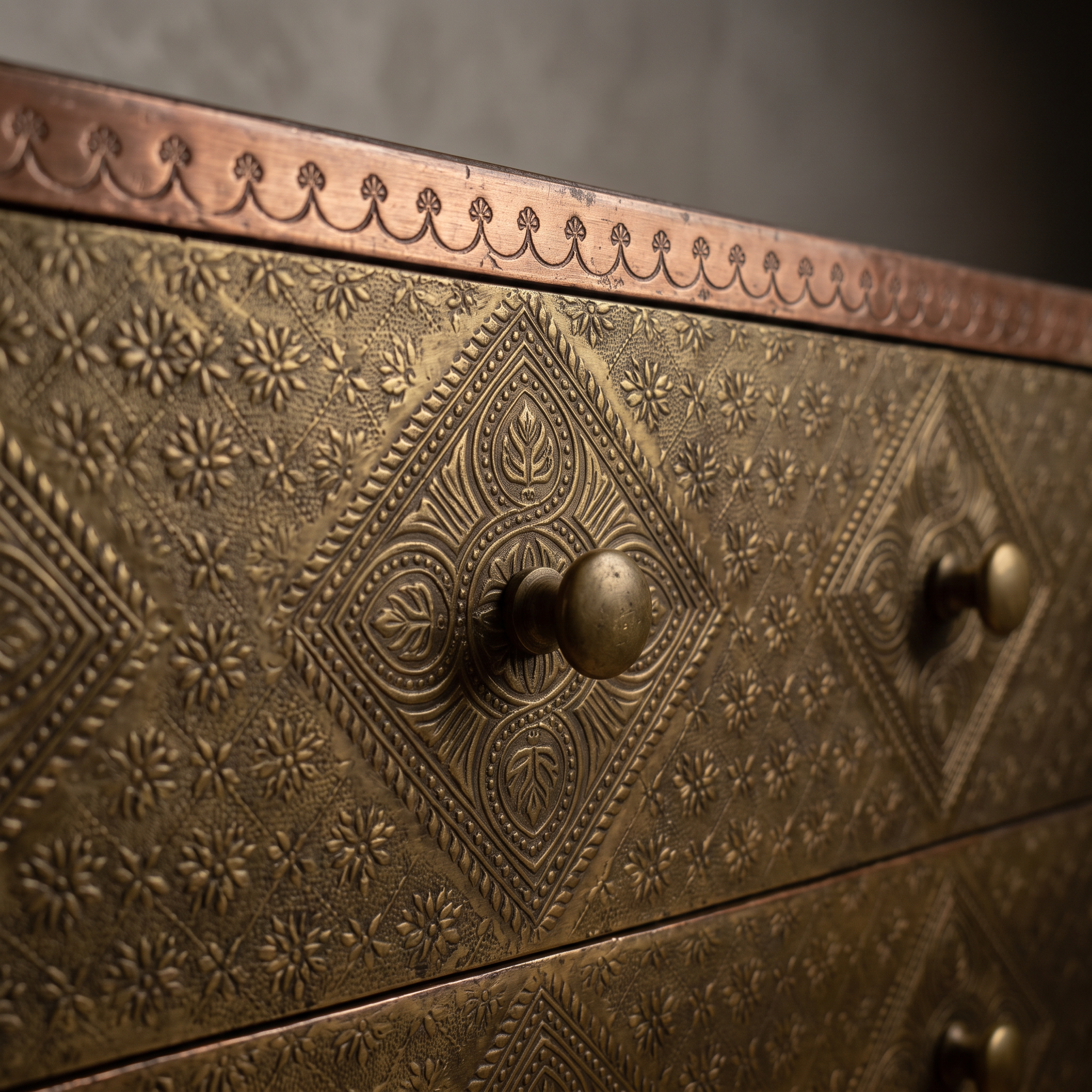 Macro detail of a drawer front's repousse medallion and copper banding on The Saffron Chest Dresser