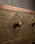 Macro detail of a drawer front's repousse medallion and copper banding on The Saffron Chest Dresser