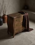 The Saffron Chest Dresser, antique brass-clad bombe chest, lifestyle hero shot in a plaster room
