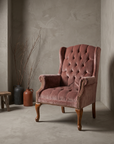Dusty rose velvet tufted wingback chair, three-quarter angle showing full silhouette and construction