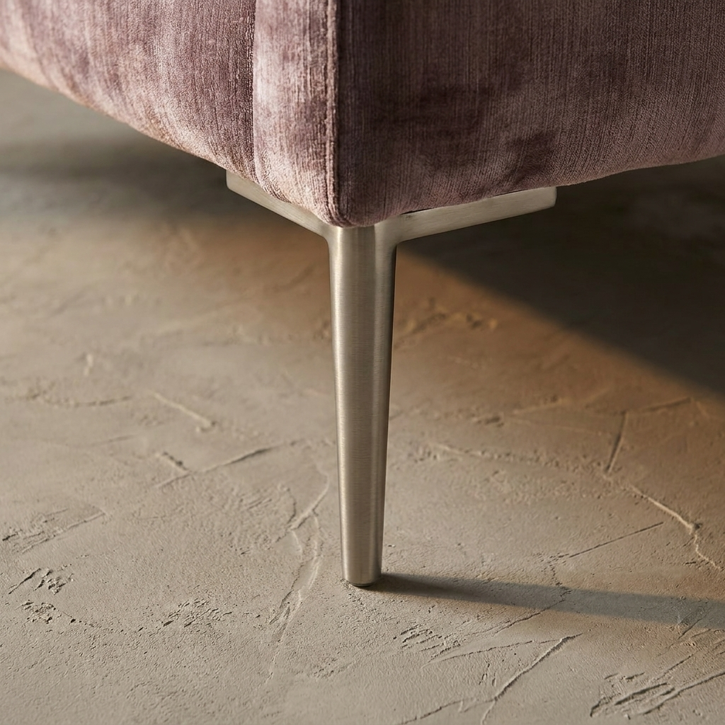 Macro detail of tapered brushed nickel chair leg on bare plaster floor
