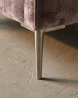 Macro detail of tapered brushed nickel chair leg on bare plaster floor