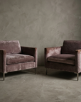 Pair of smoked lilac velvet track-arm club chairs side by side, front three-quarter view
