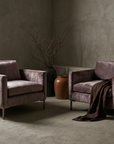 Pair of smoked lilac velvet track-arm club chairs facing each other in a greige plaster room