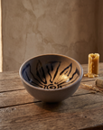 Deep stoneware bowl with broad indigo lotus petals painted inside, on a weathered oak table