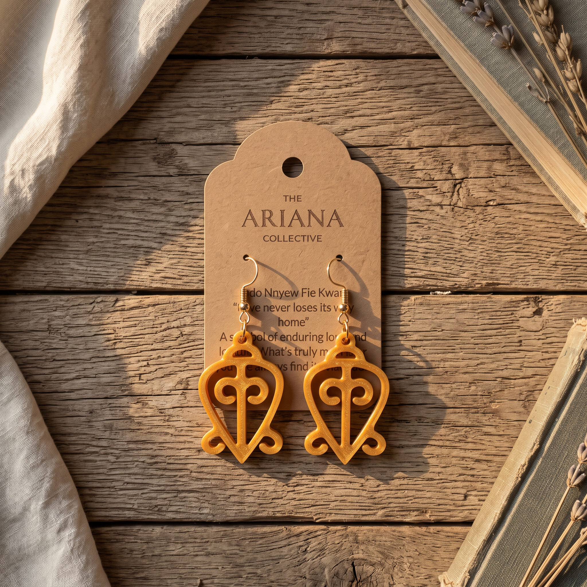 Odo Nnyew Fie Kwan Adinkra earrings laid flat with their Ariana Collective card on a weathered oak table