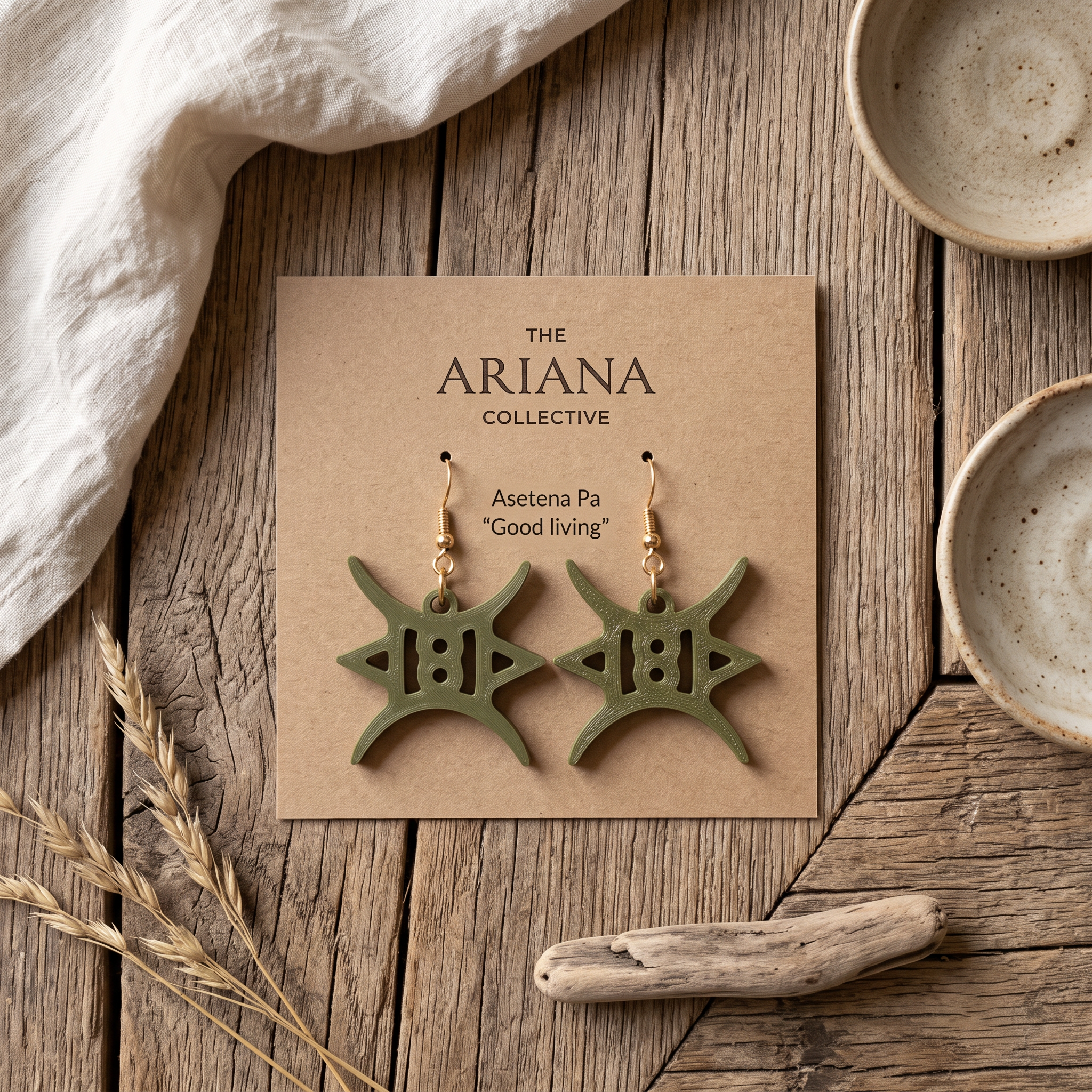 Asetena Pa Adinkra earrings in olive green on their Ariana Collective card, laid flat on a weathered oak table