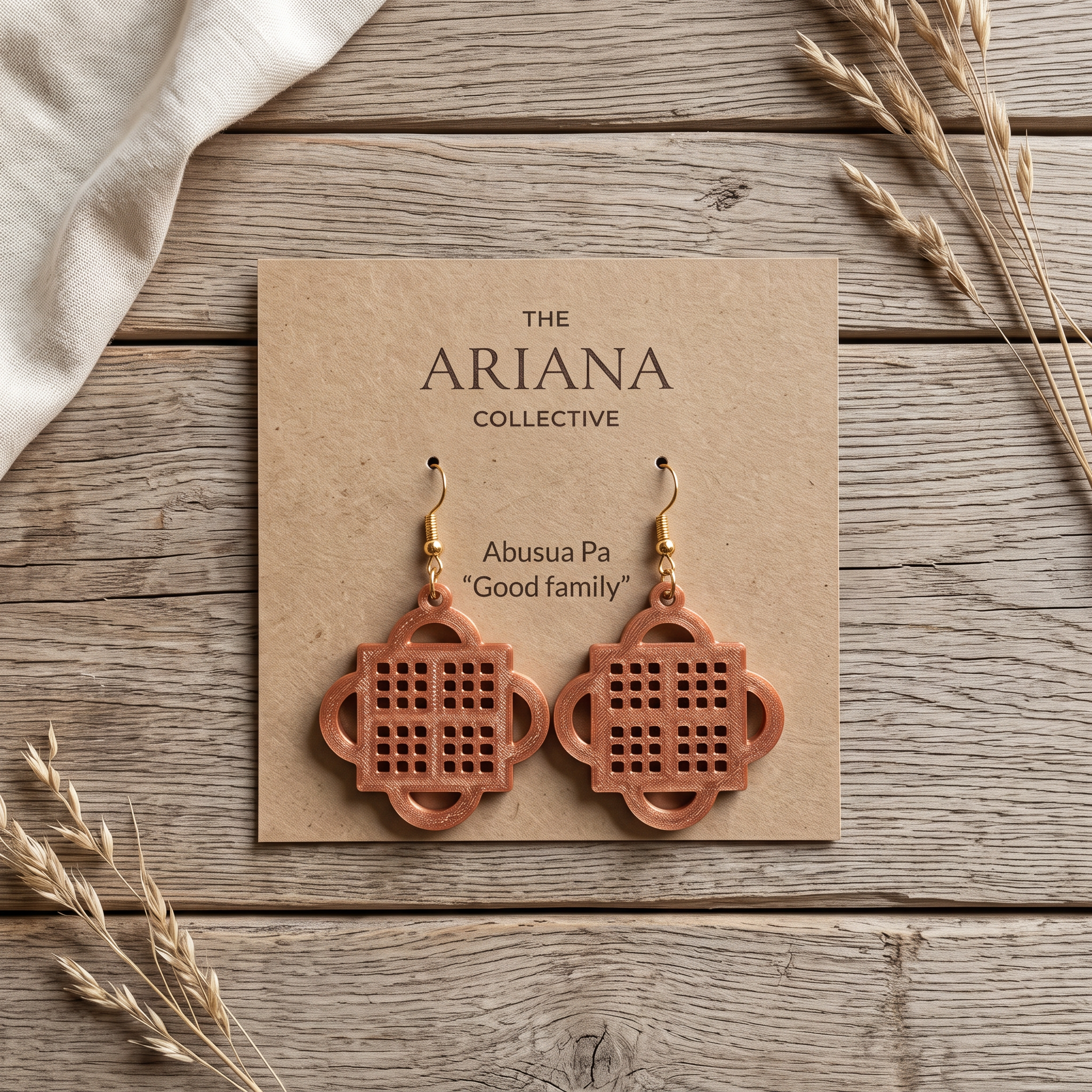 Abusua Pa Adinkra earrings in copper on their Ariana Collective card, laid flat on a weathered oak table