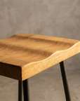 Macro detail of the Onda Stool wood grain and wave-carved seat edge