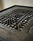 Macro detail of the Geometric Lattice cast-iron grate weave and textured frame border