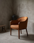 Three-quarter view of a burnt orange woven armchair showing form and construction