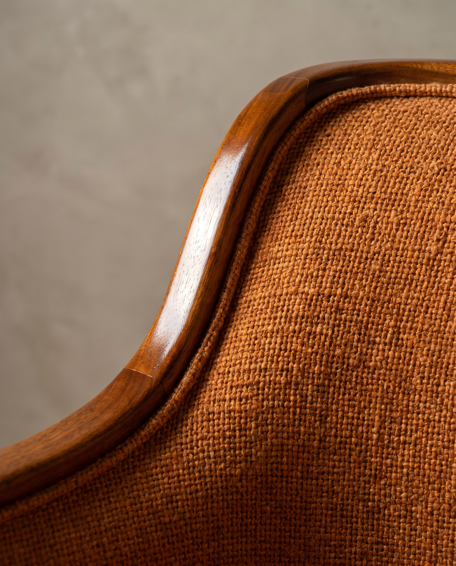 Macro detail of the walnut wood arm rail and woven burnt orange upholstery