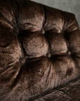 Raking macro across the tufted back cushion showing the directional pile and worn patina of the crushed velvet