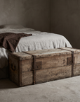 Antique pine trunk at the foot of a bed used as a bench