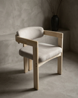 Three-quarter view of a single sueded white armchair showing the pale ash frame, square arm rail and floating crescent back cushion