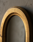 Macro detail of the arch crown of the mirror showing the continuous rounded bead and age wear around the curve