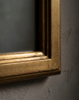 Macro detail of the lower corner of the giltwood frame showing worn gold leaf, gesso crackle and red bole beneath