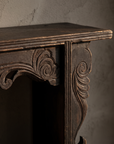 Macro detail of carved corner bracket scrollwork and wear-through patina
