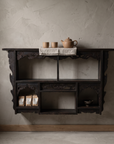 Antique carved black wall shelf styled as a home tea nook with a clay teapot, cups, and loose tea