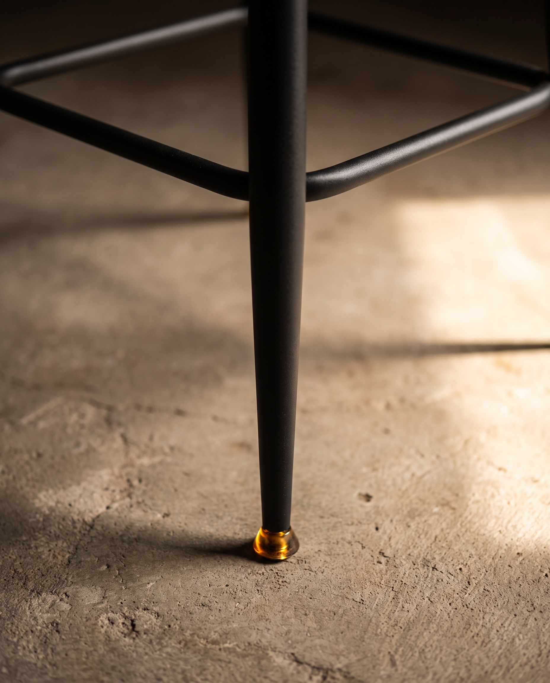 Detail of the tapered black metal leg with brass glide and diamond stretcher