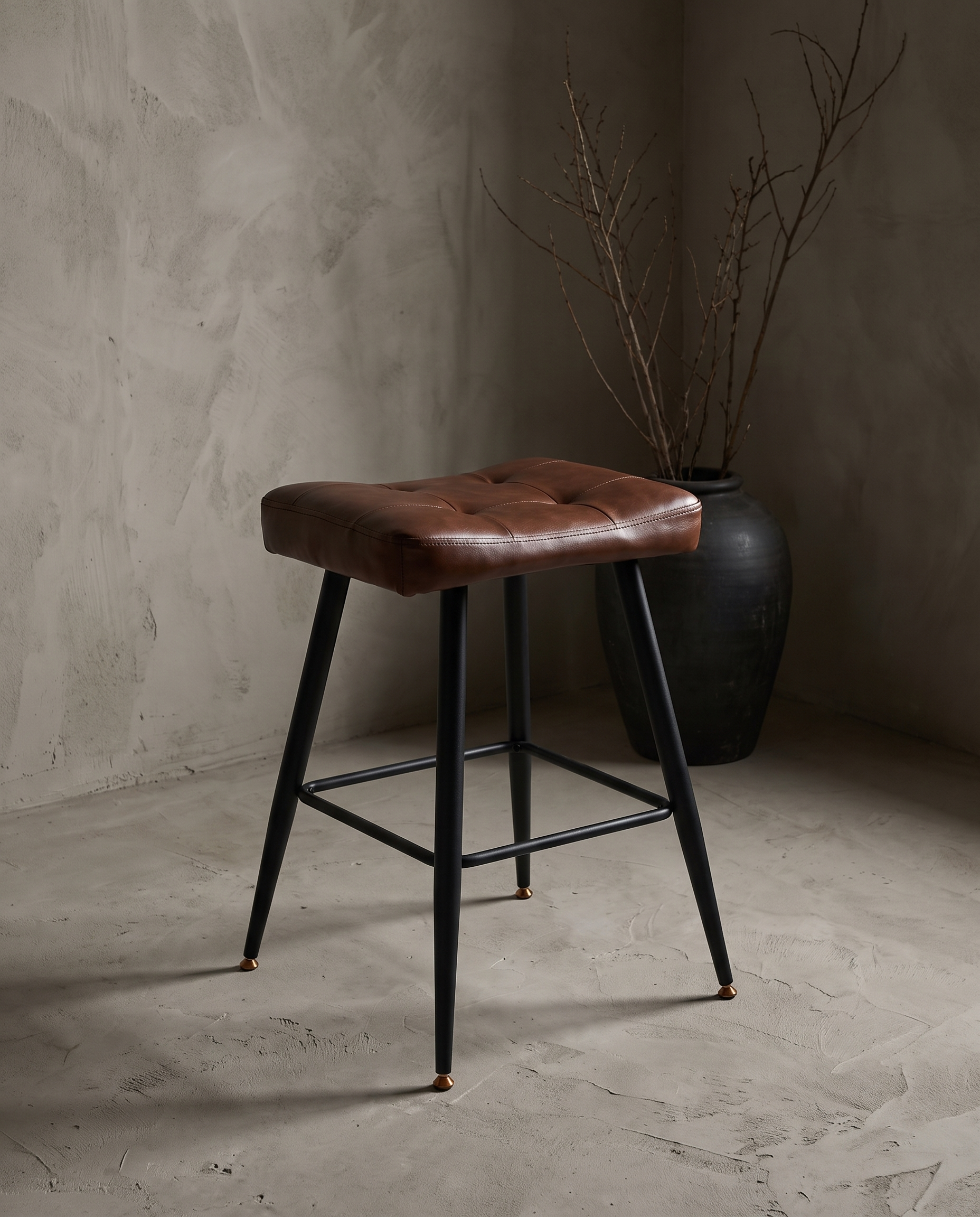 Three-quarter view of the pleather saddle counter stool showing the tufted seat and tapered legs