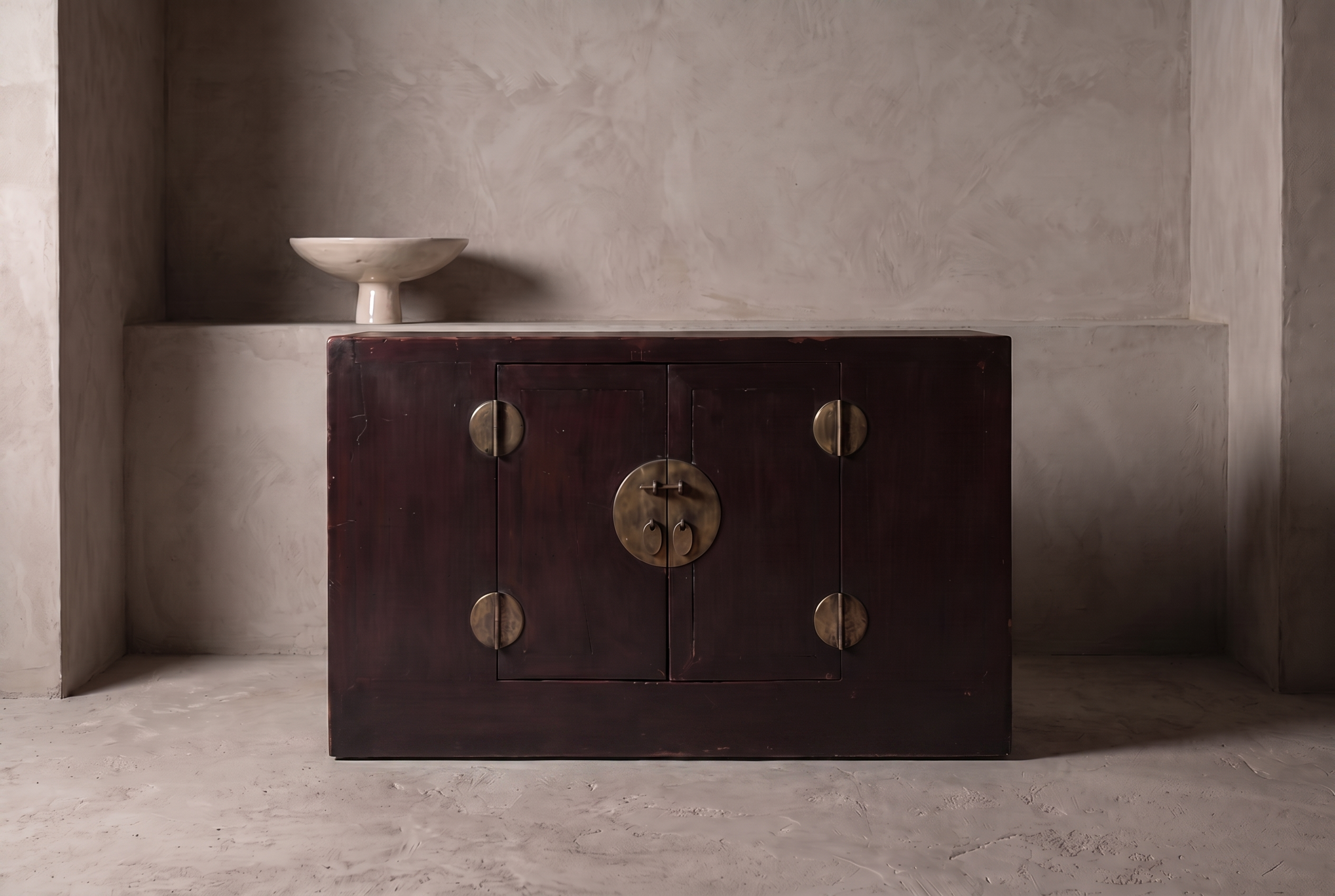 Antique Chinese oxblood lacquer cabinet, lifestyle view in a greige plaster room, matte dark oxblood finish, perfectly flush plinth base, Spanish ceramic pedestal bowl accent
