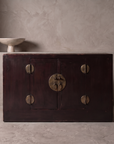 Antique Chinese oxblood lacquer cabinet, lifestyle view in a greige plaster room, matte dark oxblood finish, perfectly flush plinth base, Spanish ceramic pedestal bowl accent