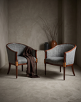 Pair of vintage grey-blue bouclé barrel-back chairs styled together in a greige plaster room