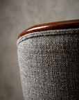 Macro detail of the grey-blue bouclé weave and mahogany top rail at the back cushion