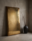 Three-quarter view of the brass panel mirror showing its folded corner construction
