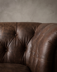 Macro detail of the diamond button tufting on The Umber Chesterfield, matte worn leather