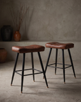 Pleather saddle counter stools, pair, against raw plaster wall