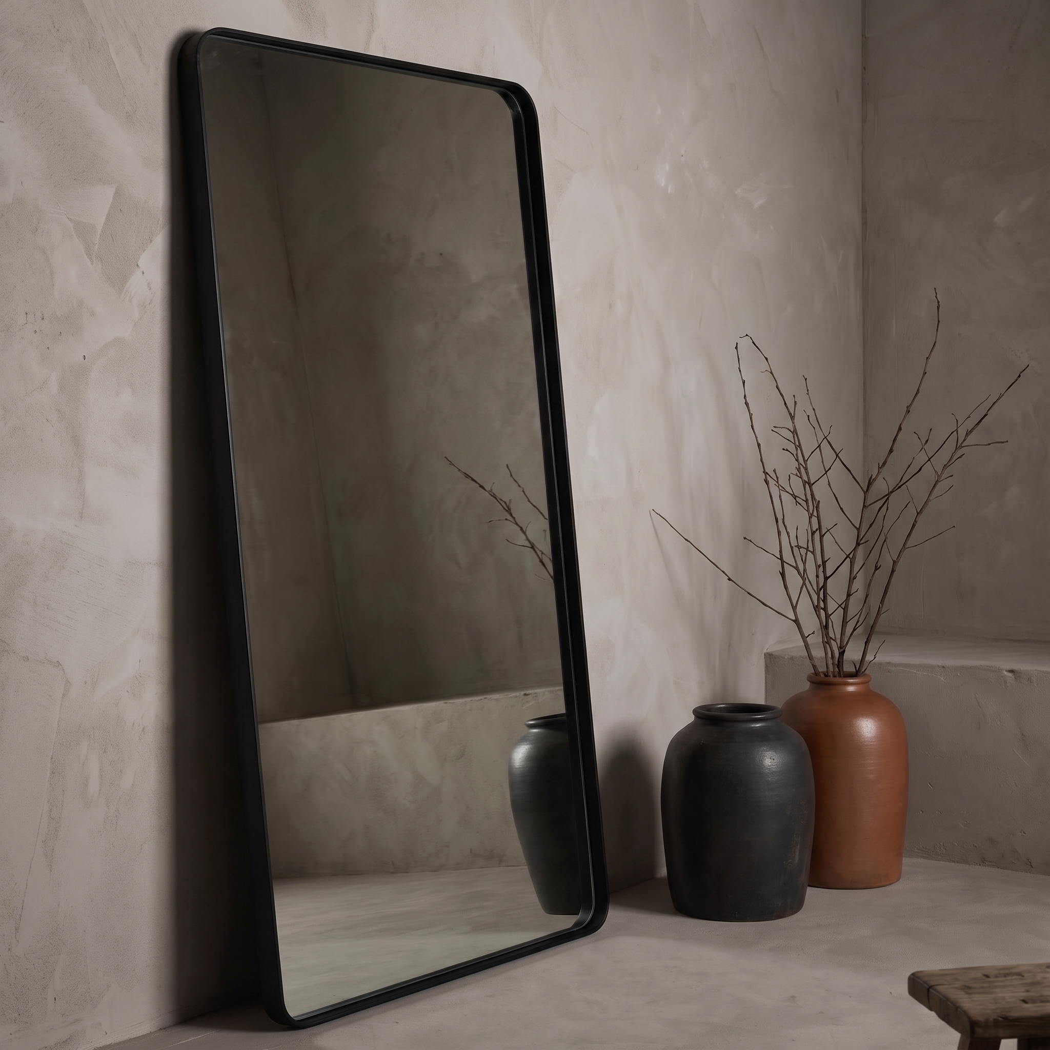 Large leaning floor mirror against raw plaster wall