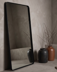 Large leaning floor mirror against raw plaster wall