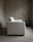 Chair and a half in white, side profile showing low arm height and plinth base