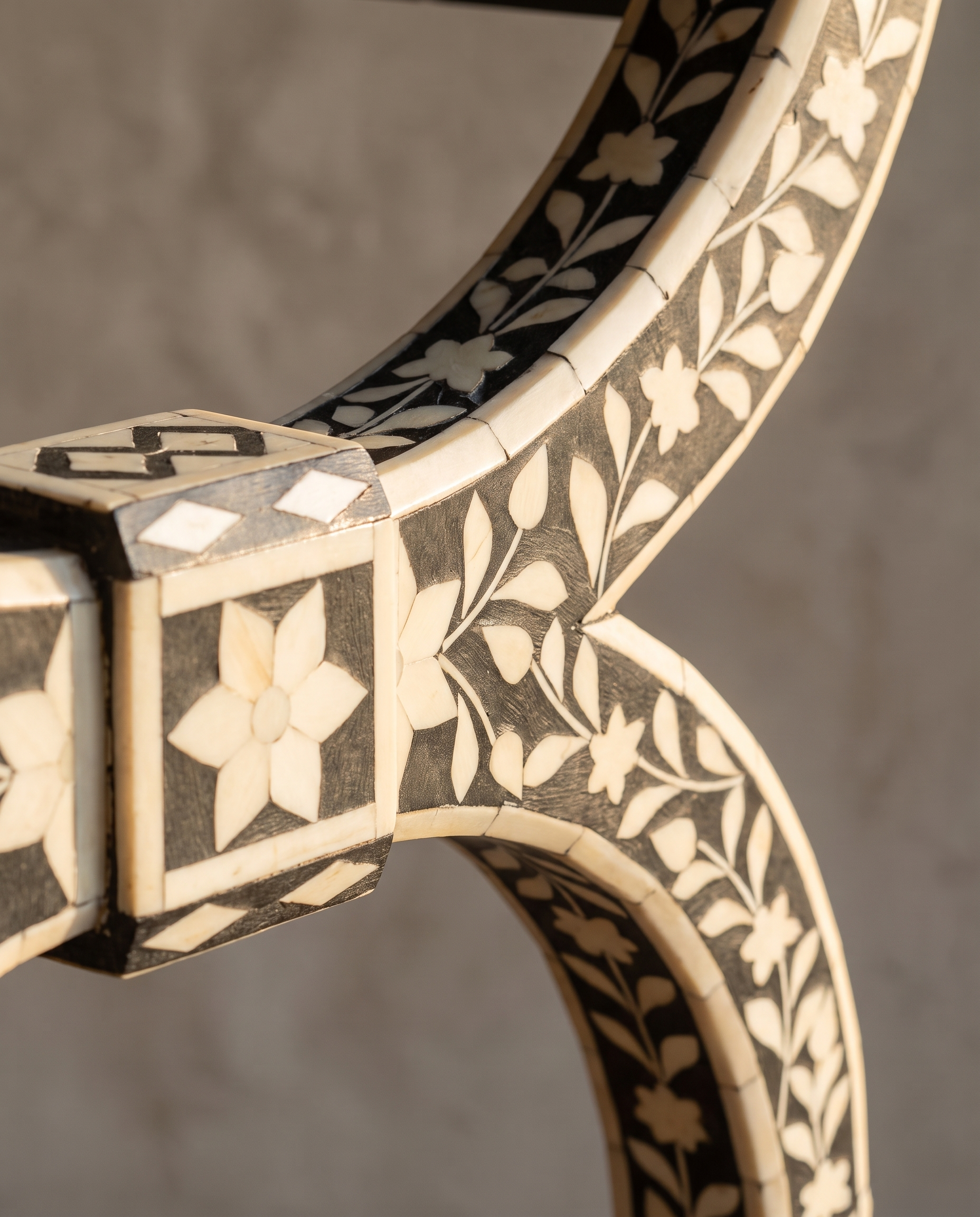 Macro detail of the bone inlay joinery block and floral vine pattern on the leg