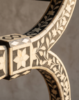 Macro detail of the bone inlay joinery block and floral vine pattern on the leg