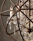 Macro detail of the Crystal Orb floor lamp's iron frame, white candle sleeves, and hand-polished crystal