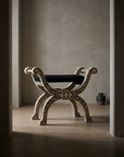 Bone inlay curule bench in a moody doorway vignette, greige plaster room