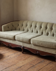 Light sage velvet tufted sofa, vintage French Provincial style, in a lived-in room corner with a window and side table
