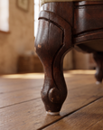 Detail of carved cabriole leg and wear on light sage velvet sofa